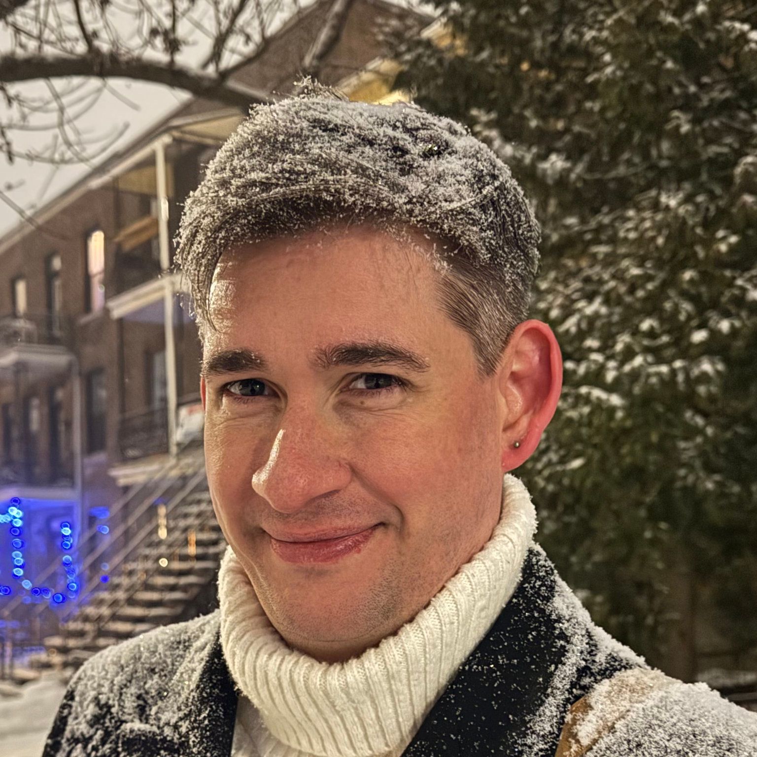 Frédéric Maquin, smiling, with snow in his hair on a Montréal street